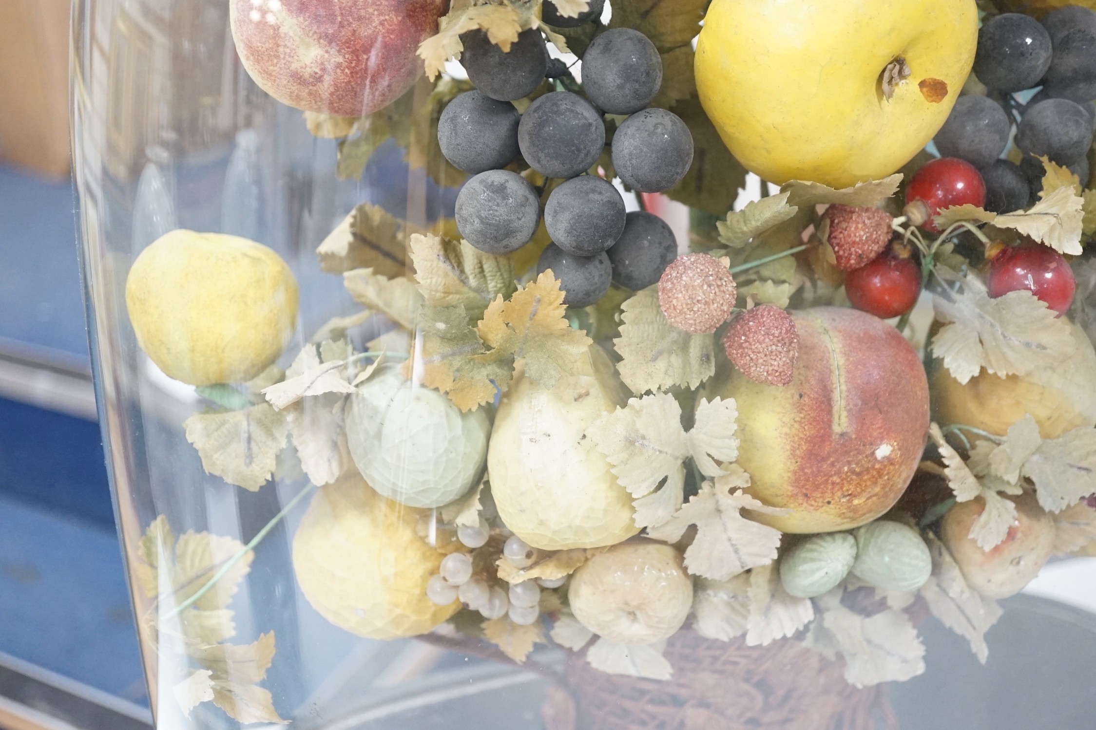 A Victorian display of papier mache fruit in a basket, under a glass dome, 55cms high